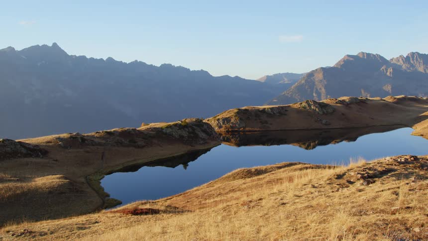A pond of water is shown near mountains