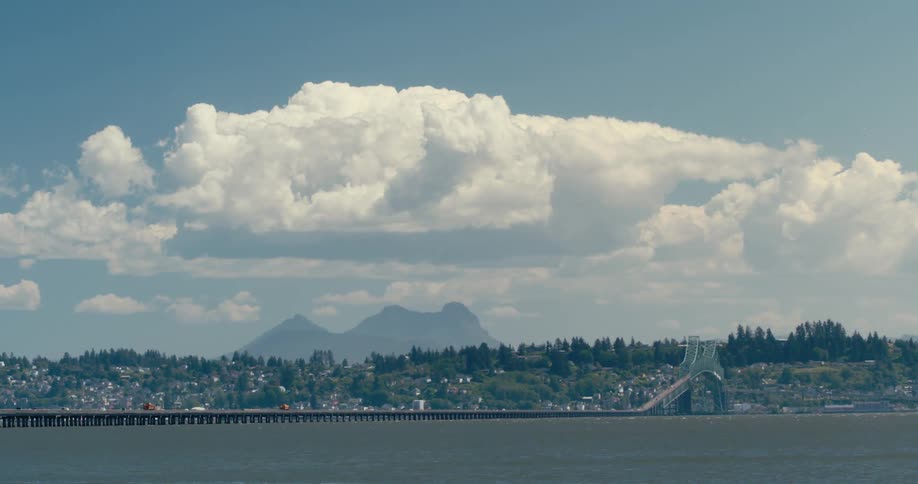 Big white cloud hanging over a mountain close to a coastal town