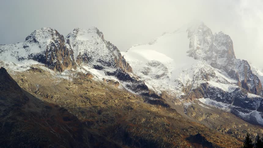 A snow covered mountain range high in a cloudy sky