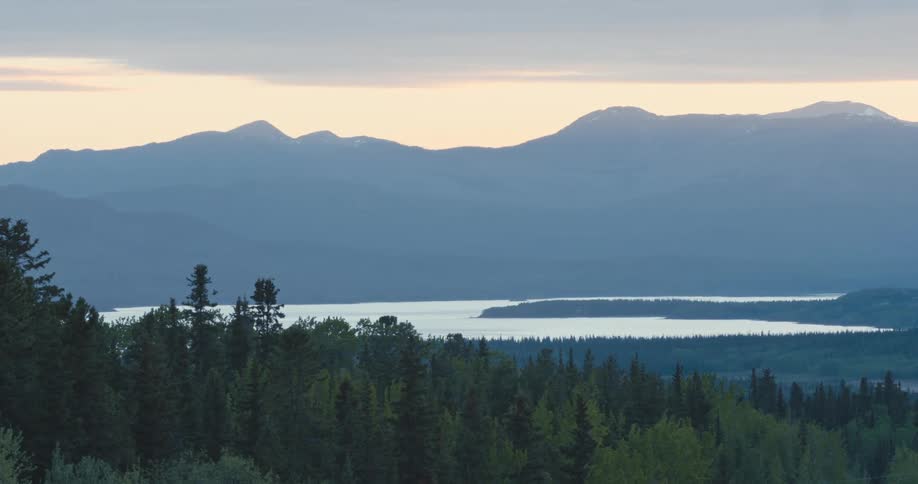 A lake divides a forest from a mountain range