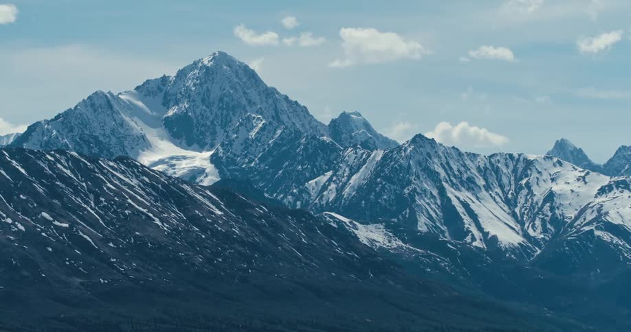 Snow covered mountain ridge with peaks high in a cloudy sky