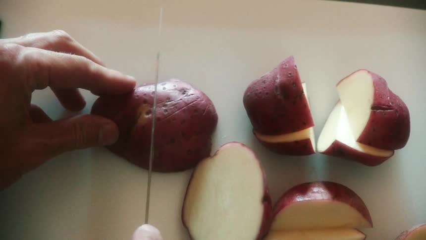 Closeup over head view of man cutting red potatoes