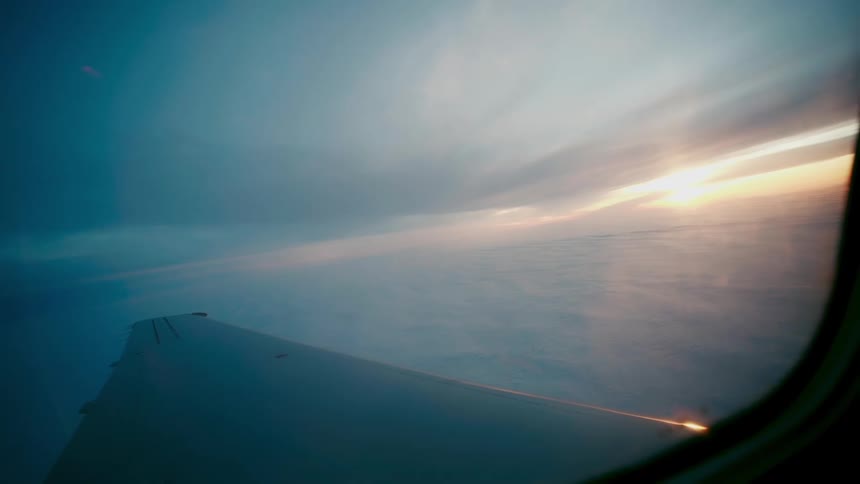 Sunset over the clouds filmed from the window of a flying airplane