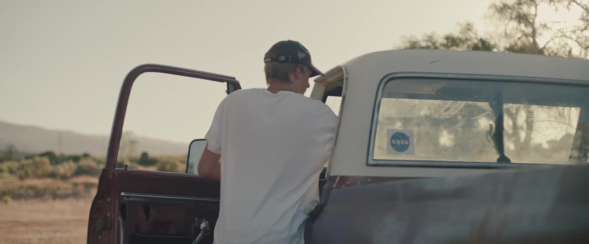 Young man carrying a handbag enters a truck parked in the countryside at morning