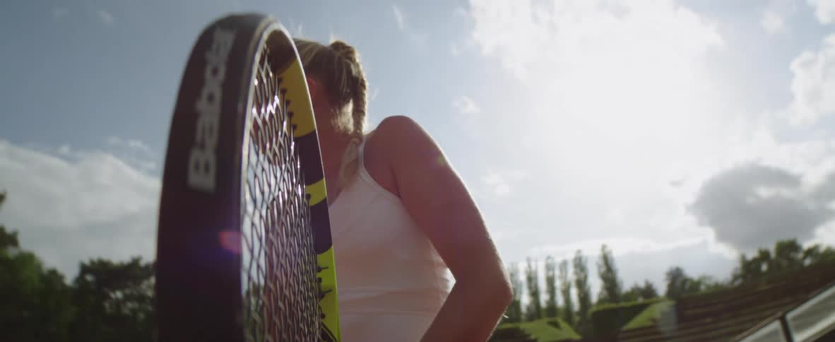 A tennis player winces as a fast moving ball hits her racket