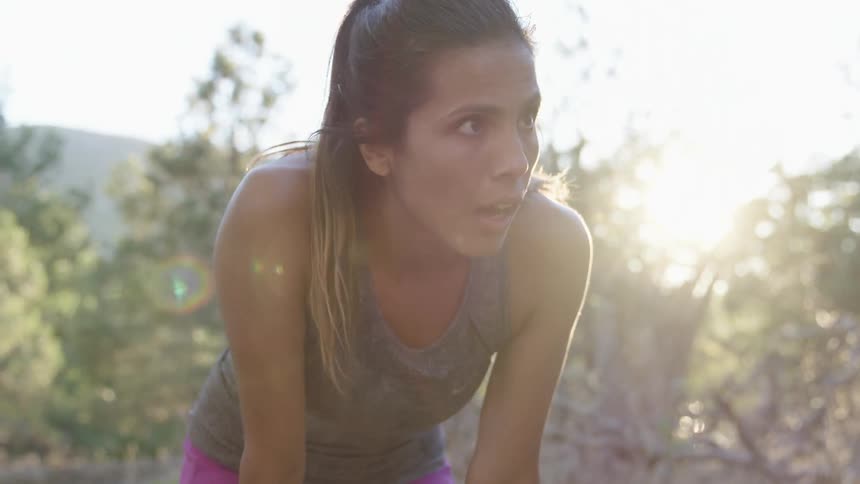 A woman runs forward before leaning forward to rest and running again