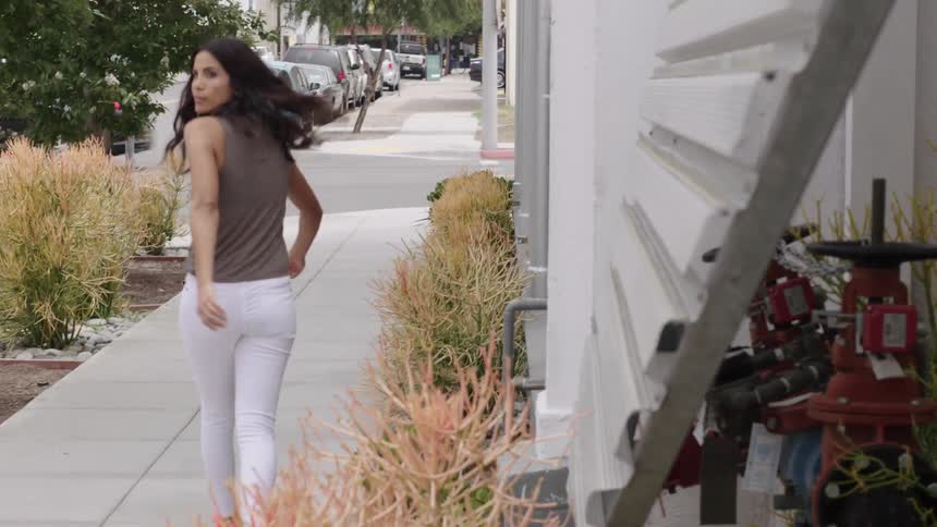 A woman walking along an urban sidewalk as traffic passes by