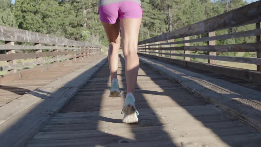 A woman jogging across a wooden bridge