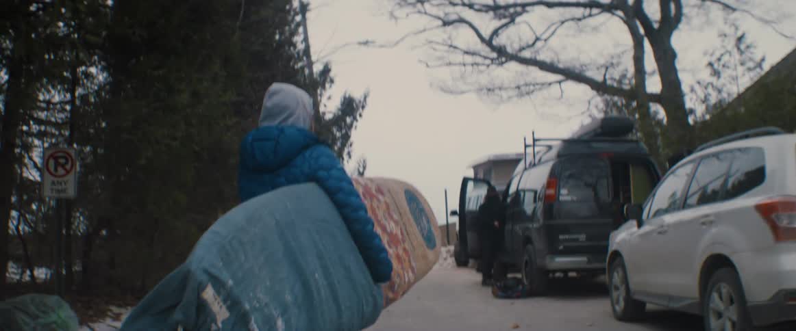 A person carrying a surfboard out to a van