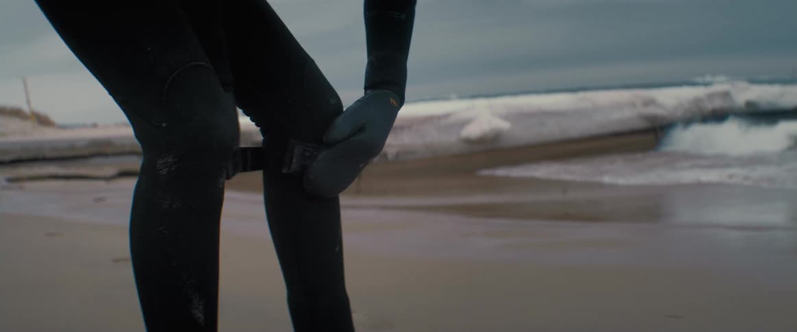 A person is putting on surfing equipment outdoors