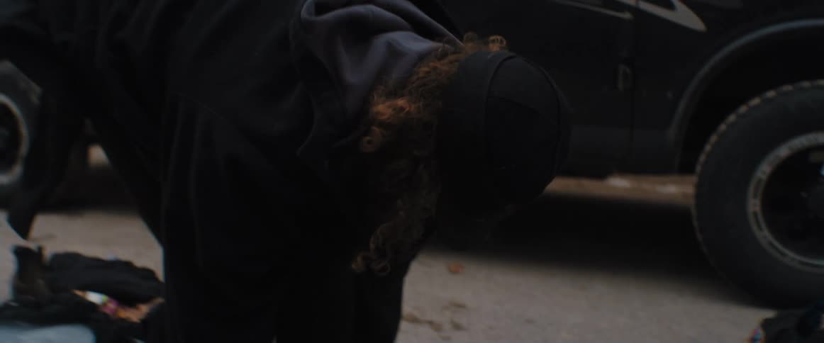 A surfer puts their wet suit and booties on by the car in the parking lot