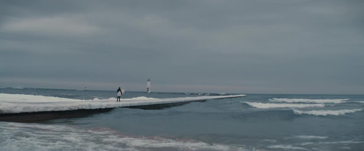 A view of a person walking outdoors on a pier in the winter