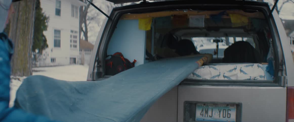 A woman is taking an item out of the trunk of her car