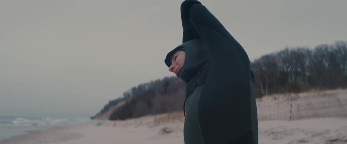 A woman stands on the beach and stretches