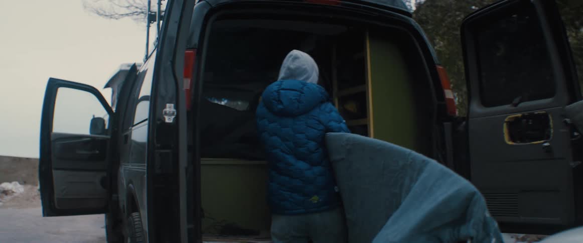Two people are putting things in the back of their van