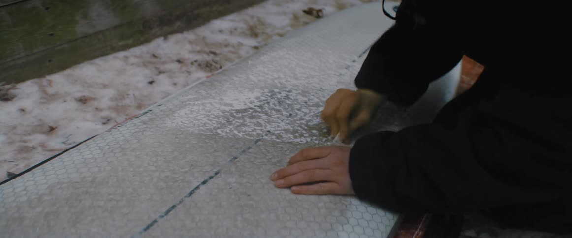 A person waxing a surfboard outdoors