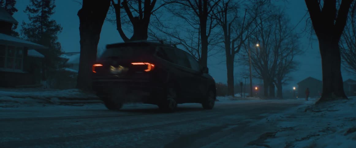 An suv travels down a neighborhood road as a person crosses the street