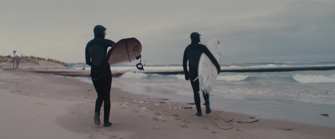 Two people are walking on the beach together