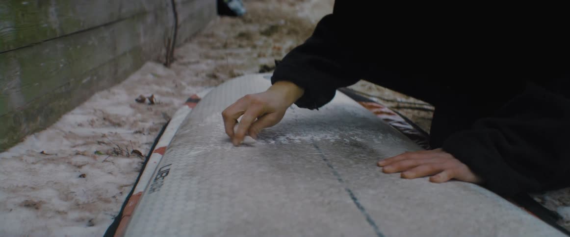 A woman is cleaning a surfboard