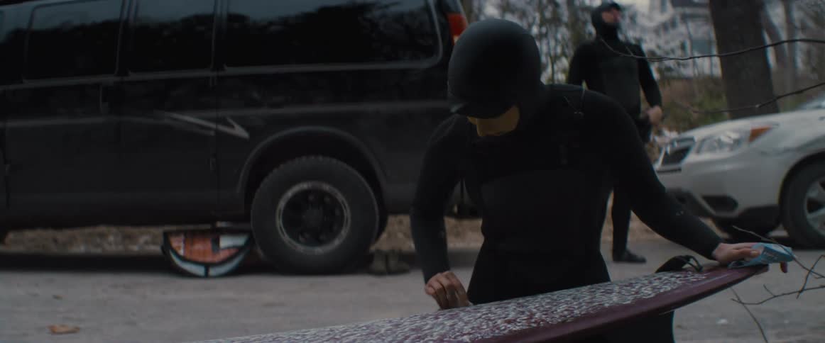 People are outdoors cleaning a surfboard