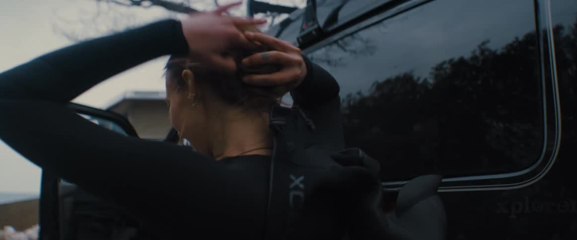 A woman is styling her hair outside of her car