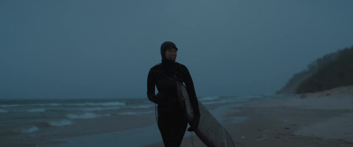 A view of a person walking on the beach in a wet suit