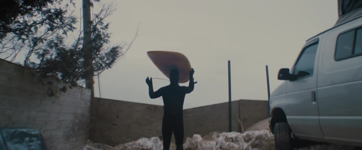 A man is holding a surfboard outdoors in spring