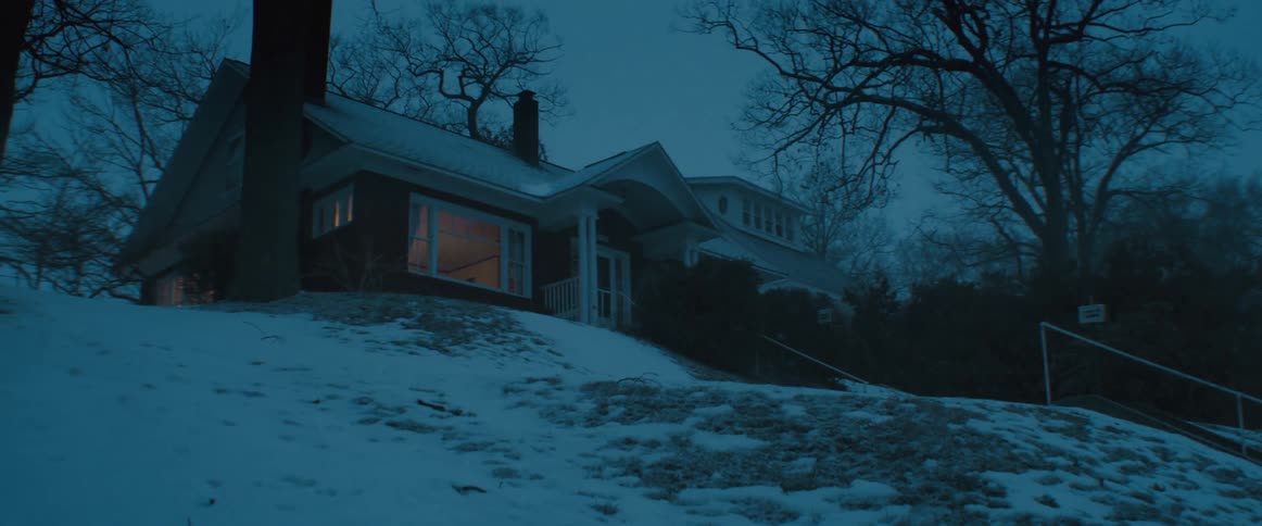 House on top of a small hill under a light snow storm at evening
