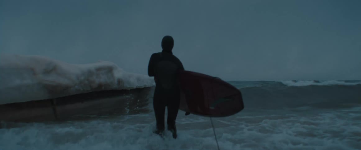 A man is surfing in ocean water at dusk