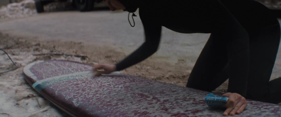 A woman waxing a surfboard