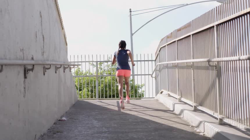 A woman runs up a ramp with a fence during daylight