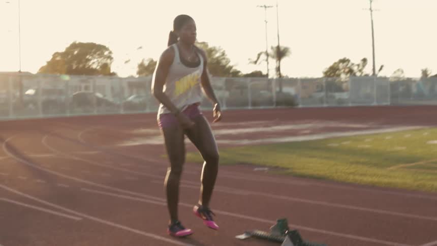 A woman jumps up and down stretching preparing on a running track