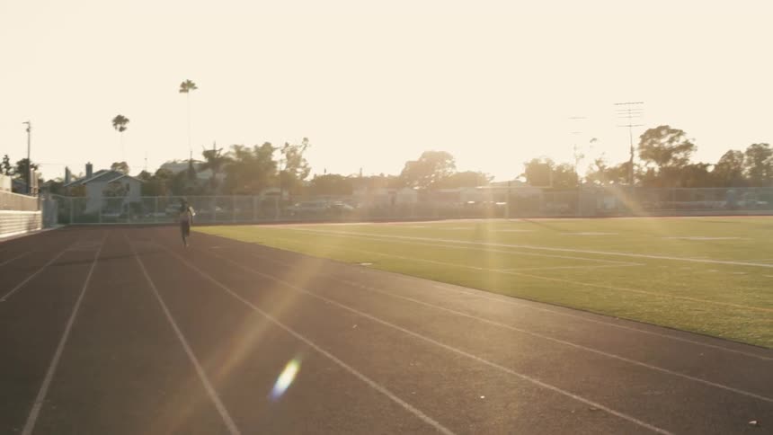 A woman comes running past a track at sunset