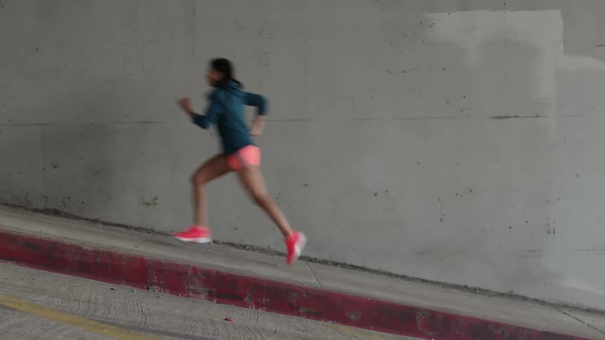 A woman on a sidewalk runs up a hill