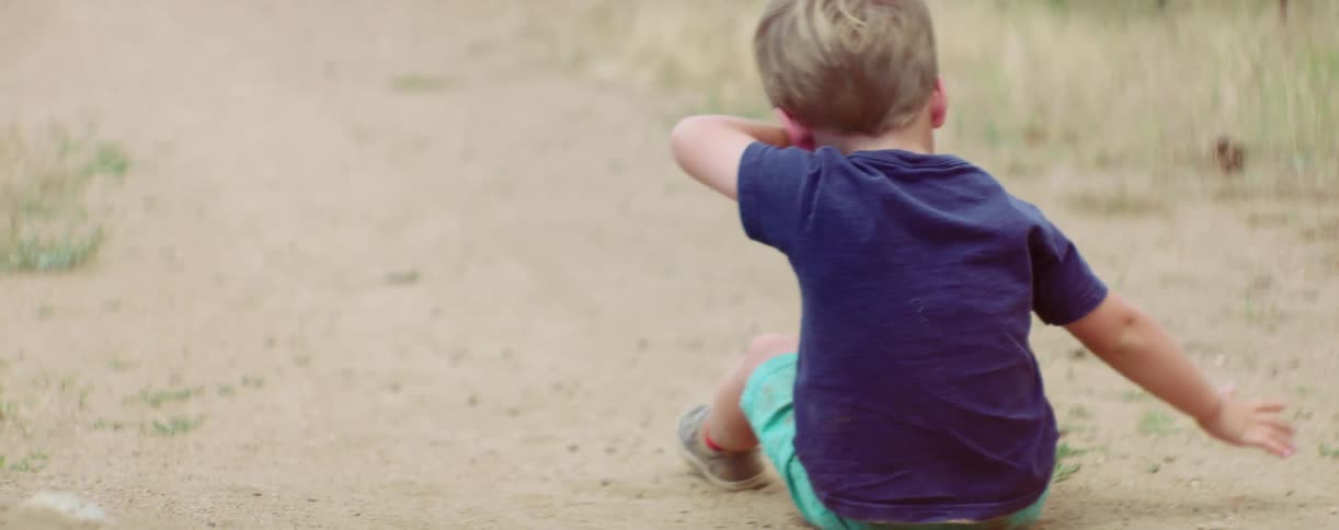 Little boy sitting and scooting in the dirt