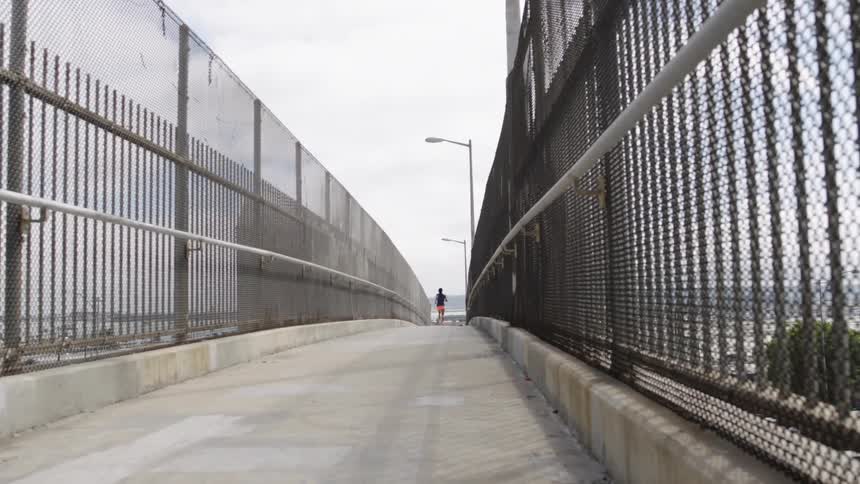 Woman jogging across a foot bridge