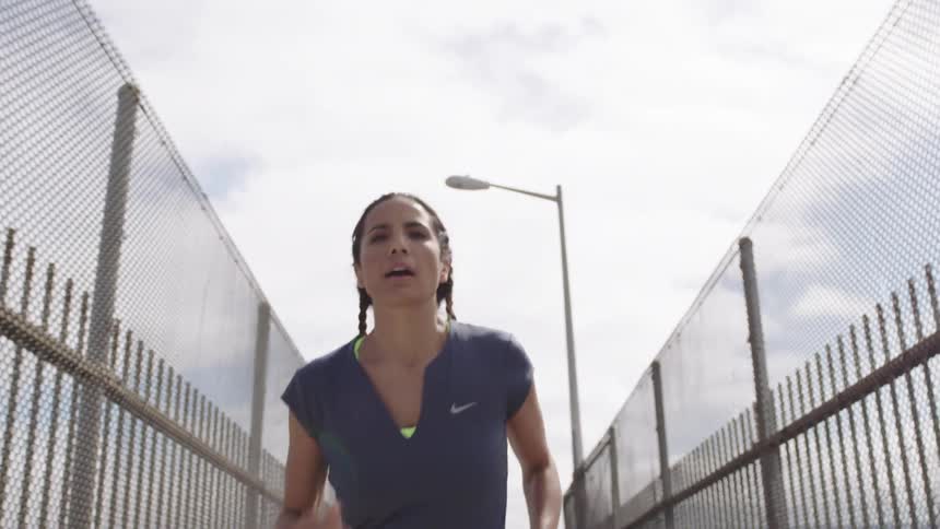 A woman jogging up a bridge ramp