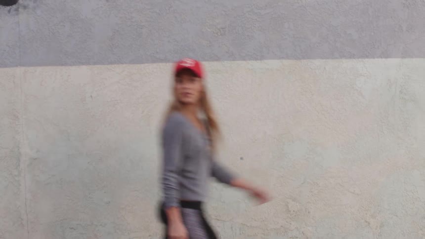 A woman walking past a stucco wall