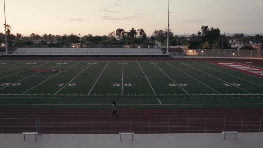A woman is walking along the track around a football field