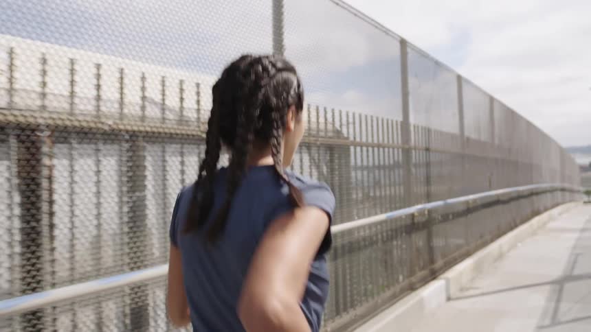 A woman jogging across an overpass bridge