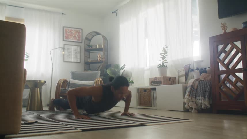 A man doing push ups in his living room on a bright day