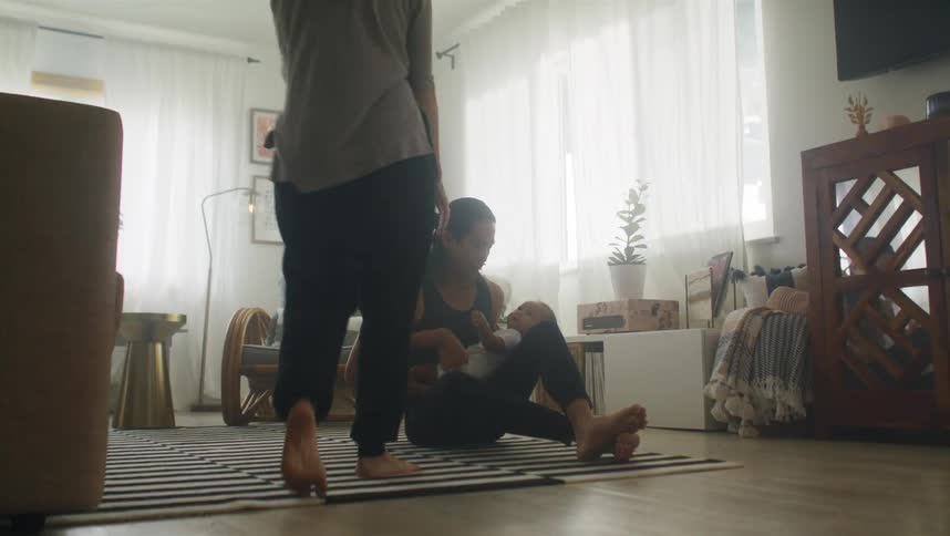 A mother brings the baby out of the room after playing with the father