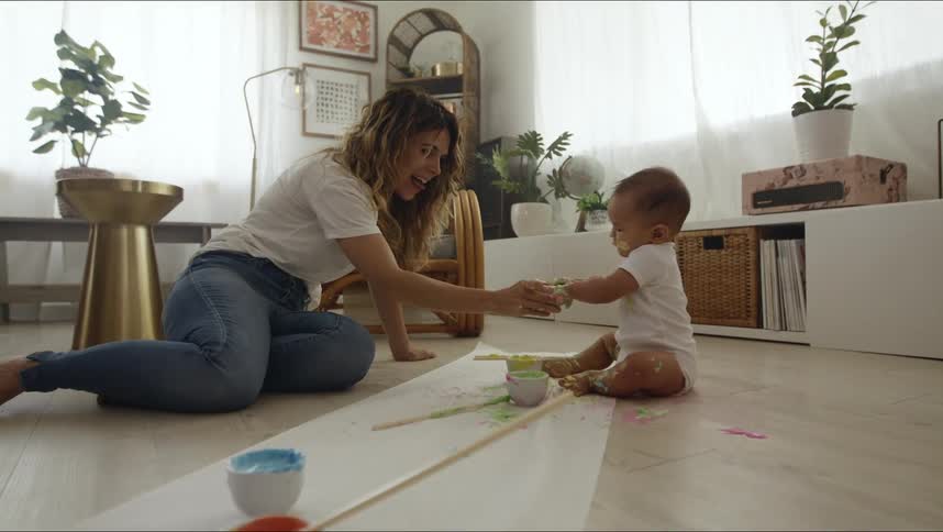 A woman sits on the floor playing with an infant