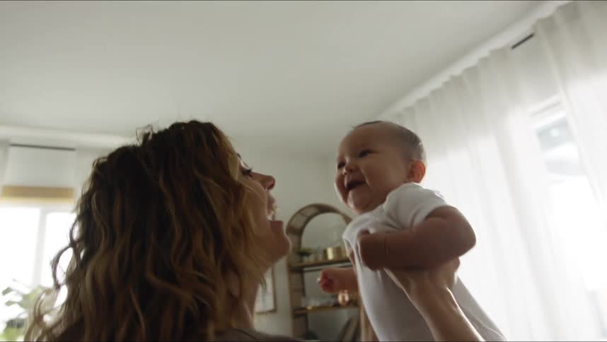 A woman is lifting her baby around the room