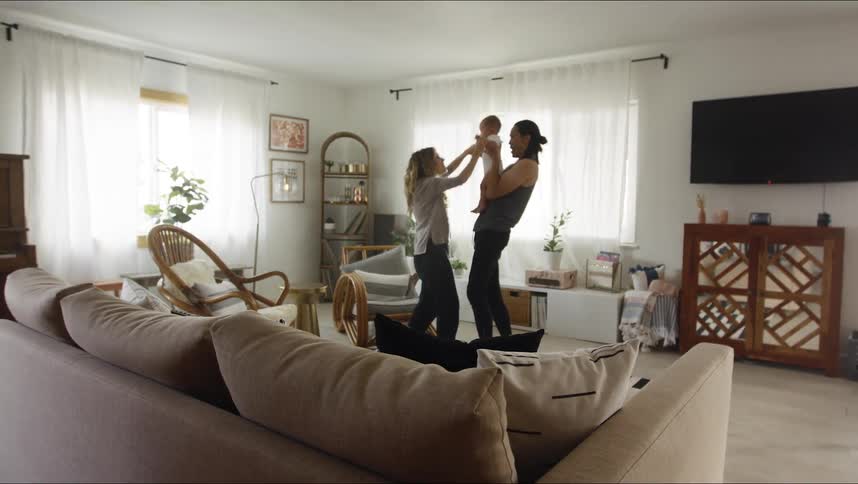 A mother and father dancing with a baby in a room
