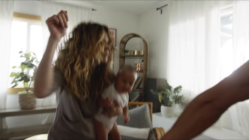 Mother holding a baby and dancing with her husband at the living room