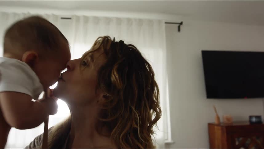 A woman throws her baby up in the air and gives him a kiss