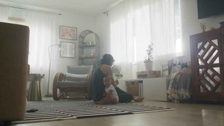 A woman sits on the floor with her baby
