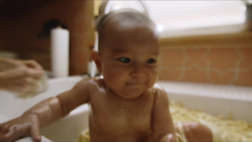 Baby sits and splashes in kitchen sink full of noodles