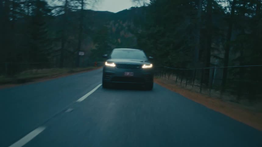 Car travels on a road with trees on each side as a mountain sits in the distance